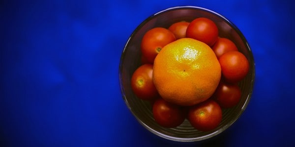 Tomatoes and an orange, photo by Jon Bunting